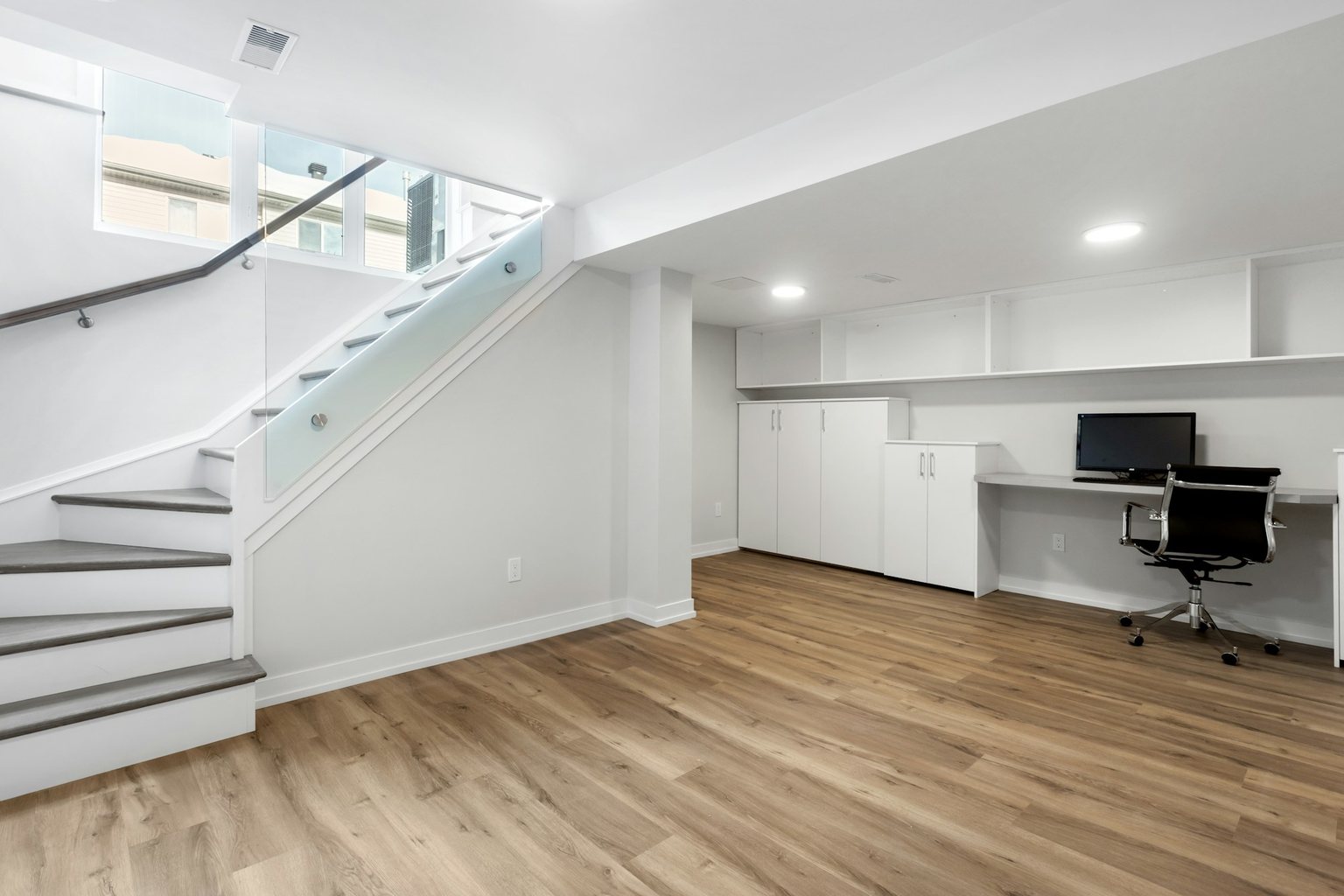 Finished basement with a home office, stairs and wood-look flooring