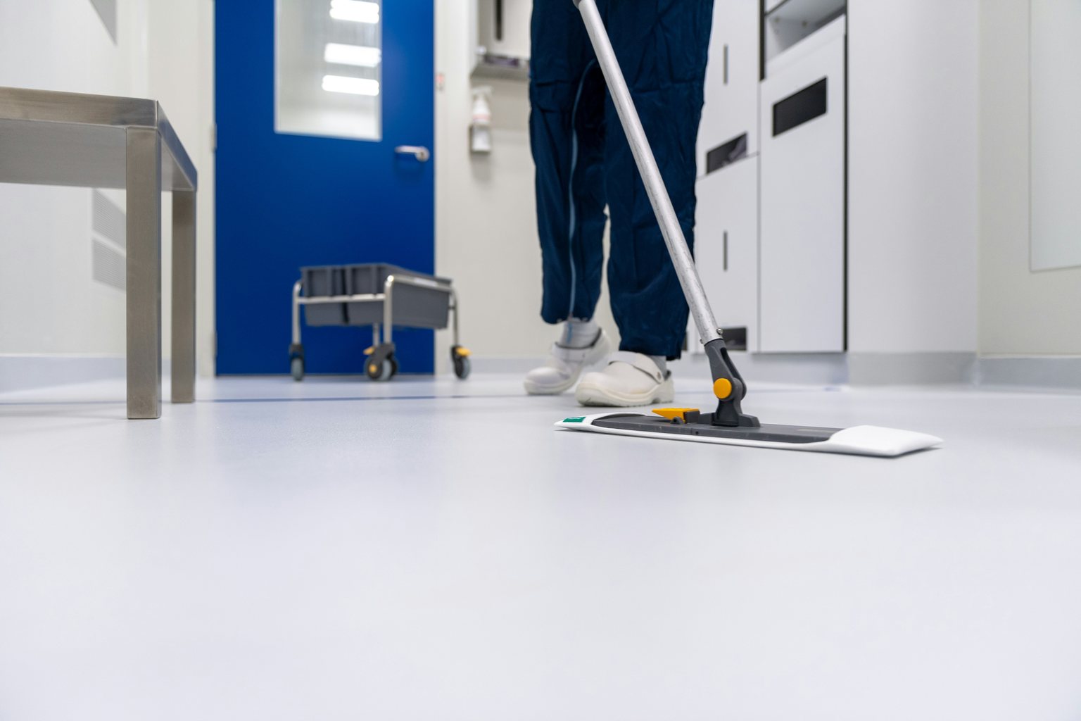 Worker mopping a smooth floor in a clinical laboratory corridor