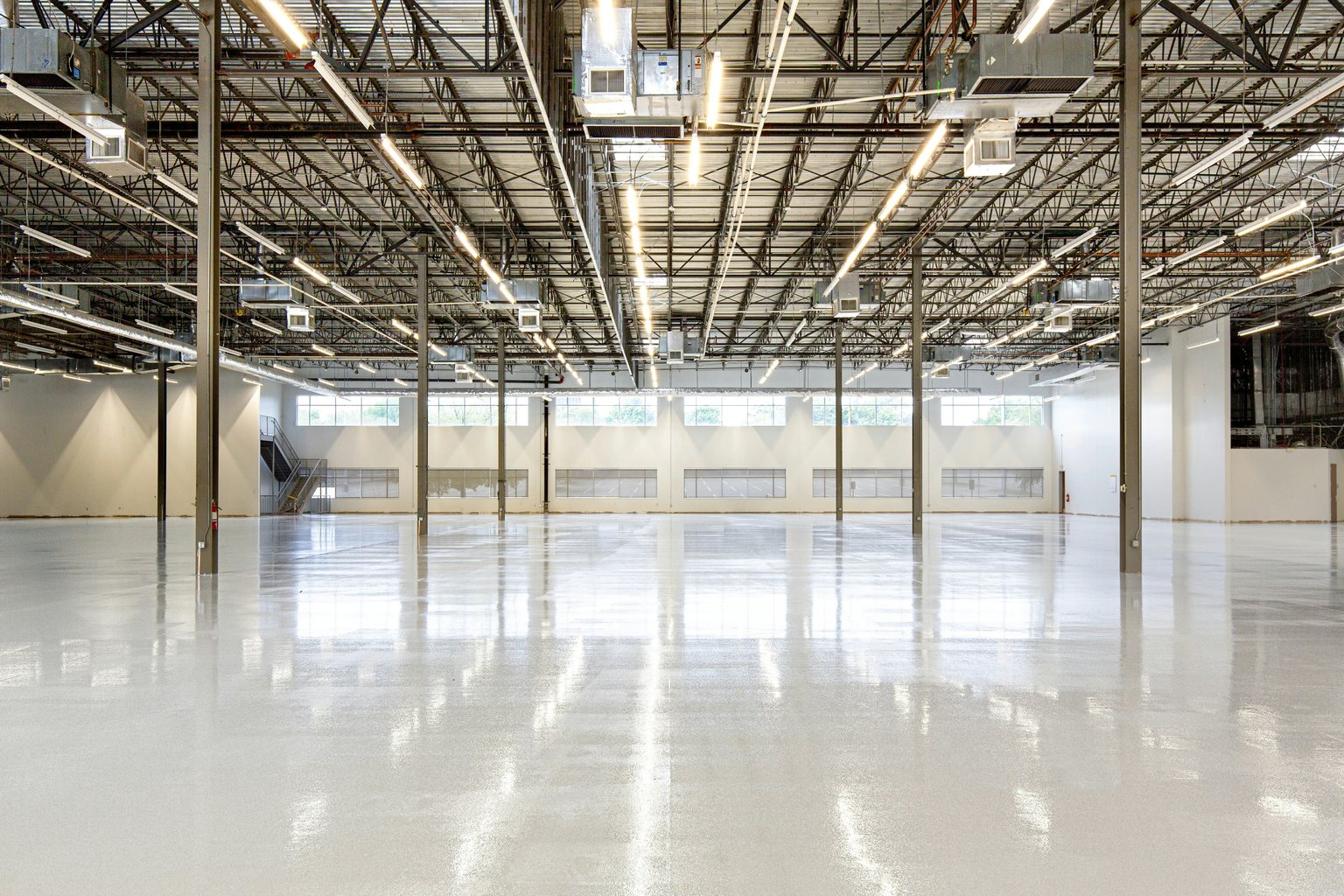 Wide commercial interior with a light gray floor and exposed ceiling structure