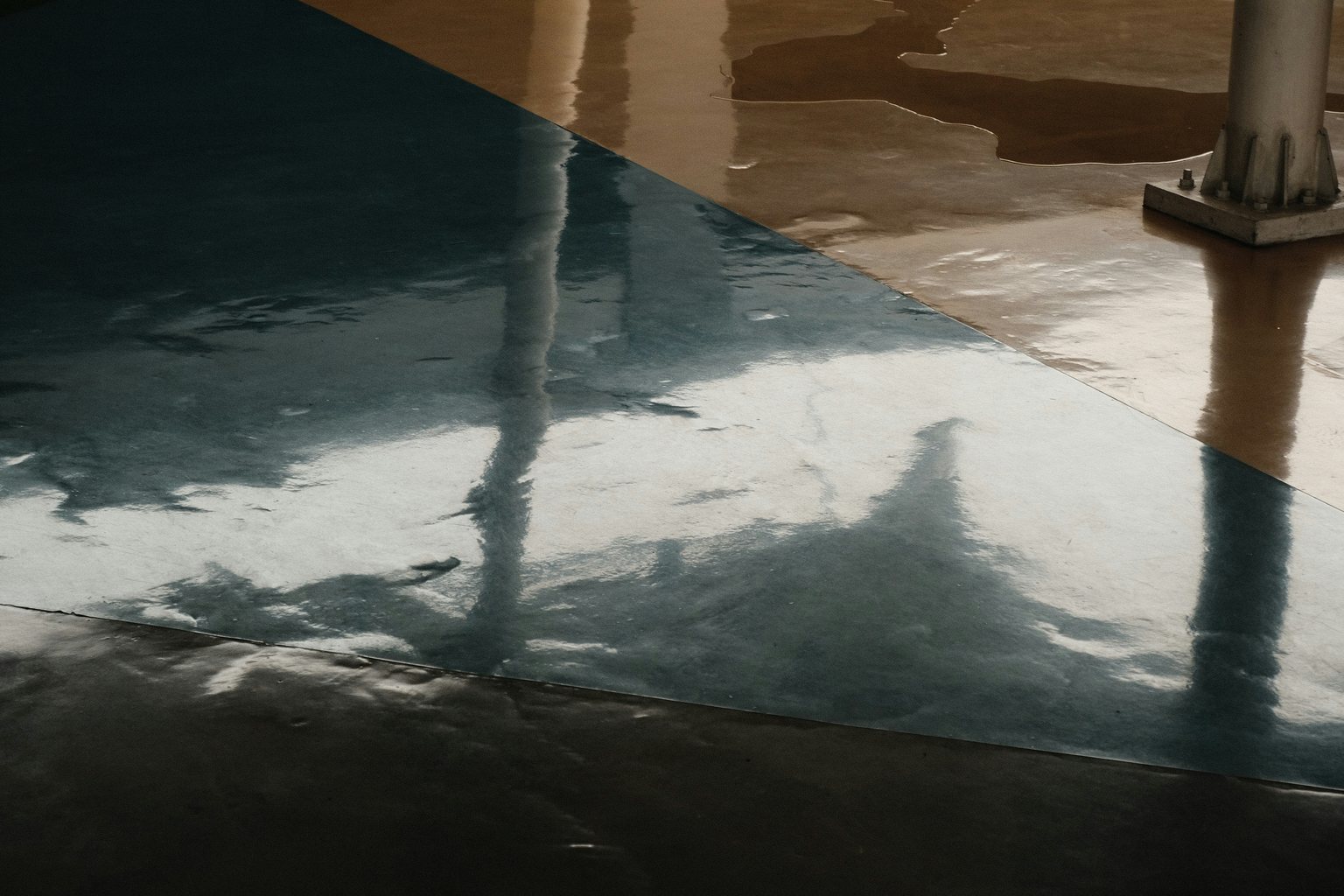 Glossy colored industrial floor surface reflecting columns and windows