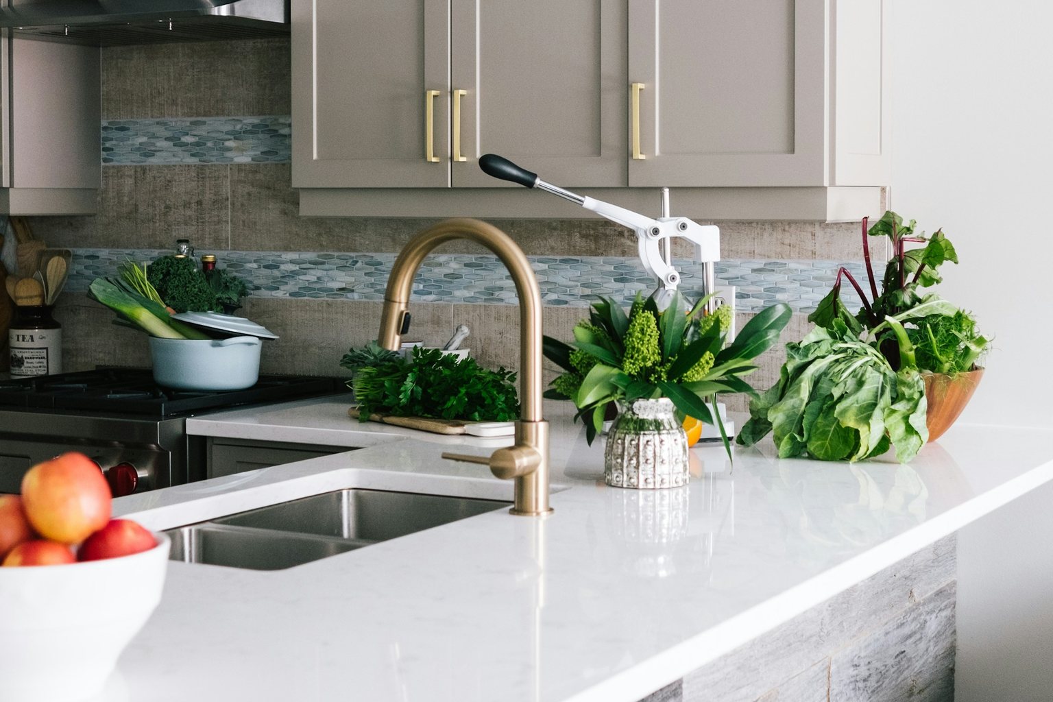 Kitchen island with white cabinets, wood stools and brass fixtures
