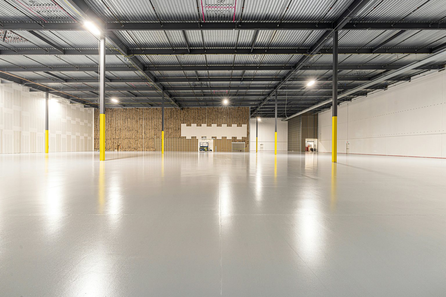 Large warehouse with a gray floor and yellow column bases