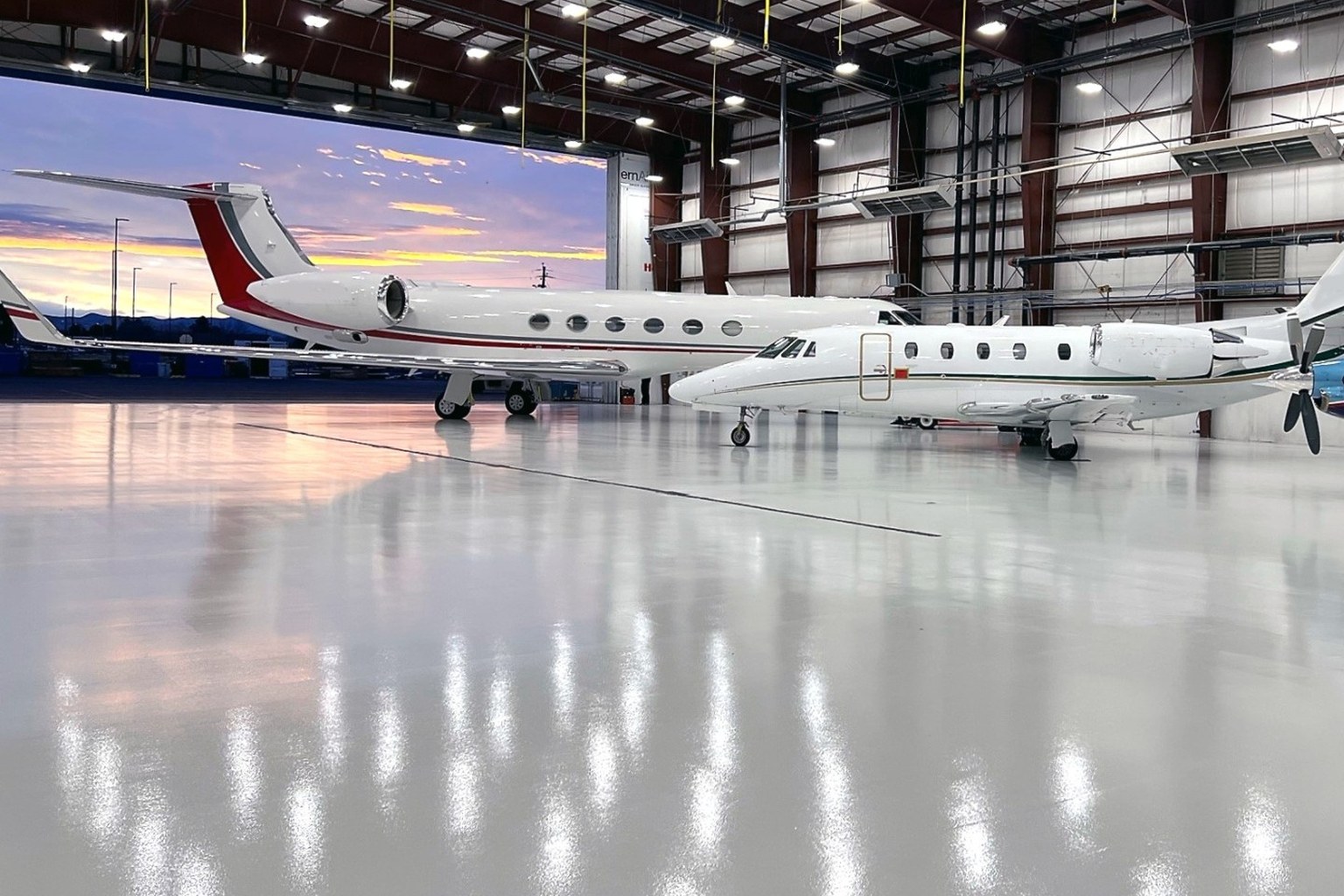 Aircraft parked inside a hangar on a reflective light gray resin floor.