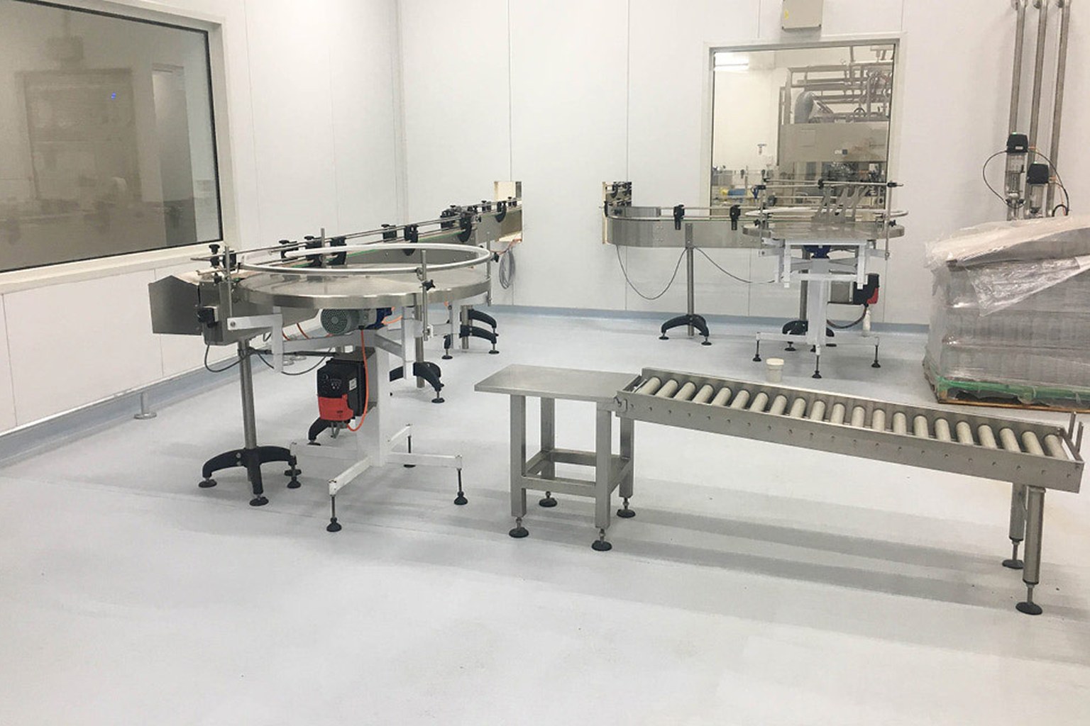 Stainless steel dairy production conveyors above a seamless light gray resin floor.